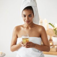 Portrait of african girl with towel on head holding glass smiling
